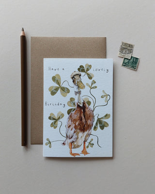 Whimsical illustration of indian runner duck wearing a tweed cap and bow tie surrounded by leaves and Have a lovely birthday text  