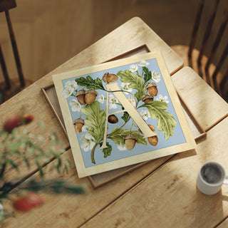 Letter A botanical alphabet art print featuring hand-painted acorns and alyssum flowers in blue and butter yellow.
