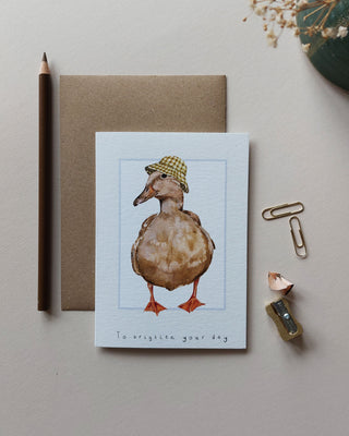 Illustrated brown duck wearing gingham hat card with text reading to brighten your day.