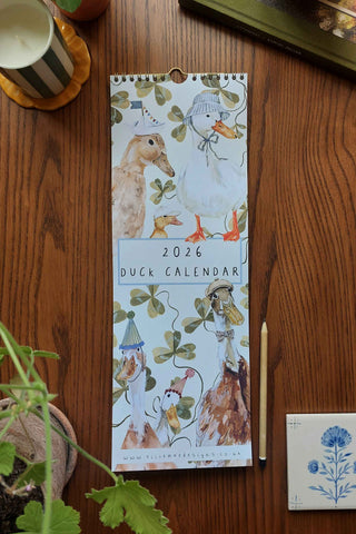 2026 Duck Calendar on a wooden surface with decorative elements.