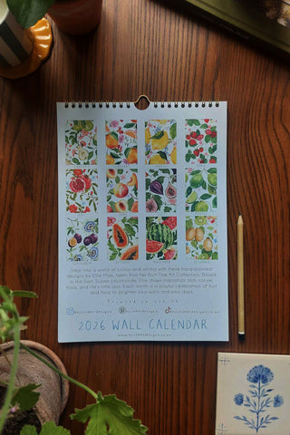 2026 wall calendar with floral and fruit designs on a wooden surface.