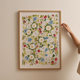 Garden strawberries print framed in thin oak frame against blank wall.