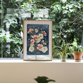Nasturtium art print, a hand painted navy blue background with olive green leaves and peachy pink nasturtium flower heads. with small text reading floral studies:nasturtium NO.6 styled amongst greenery and plants