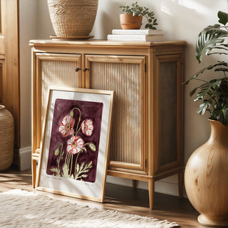 Plum coloured painted background with pink poppy flowers and text reading  floral studies: Poppy No.8 framed and styled against rattan wooden furniture