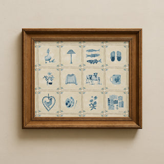 A square framed art print featuring a 3x4 grid of blue-and-cream illustrated tiles with objects like a goose, lamp, fish, sandals, flowers, sweater, elephant, mug, heart, paint palette, and newspaper. The print is mounted on a warm beige wall.